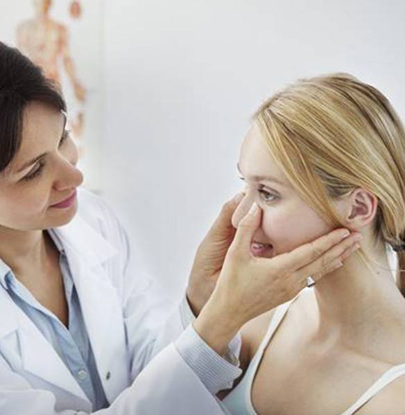 Dentist checking female patient’s facial structures for swelling
