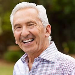 man in a plaid shirt smiling outside 