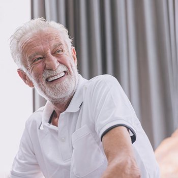 a mature man smiling with his implant dentures
