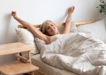 An older woman stretching after waking from a restful night’s sleep