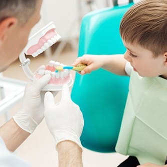 Child in dental chair practicing toothbrushing