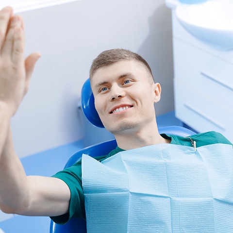 Dentist high-fiving a patient during a checkup in Powdersville