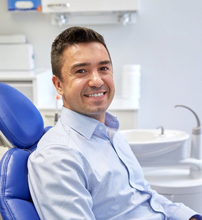 Man in blue shirt smiling in dental chair
