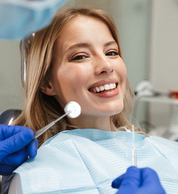 Woman in dental chair with dentist examining teeth