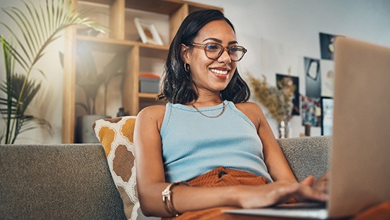 Woman smiling while working on laptop at home