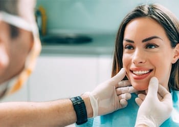 A cosmetic dentist examining a female patient’s smile