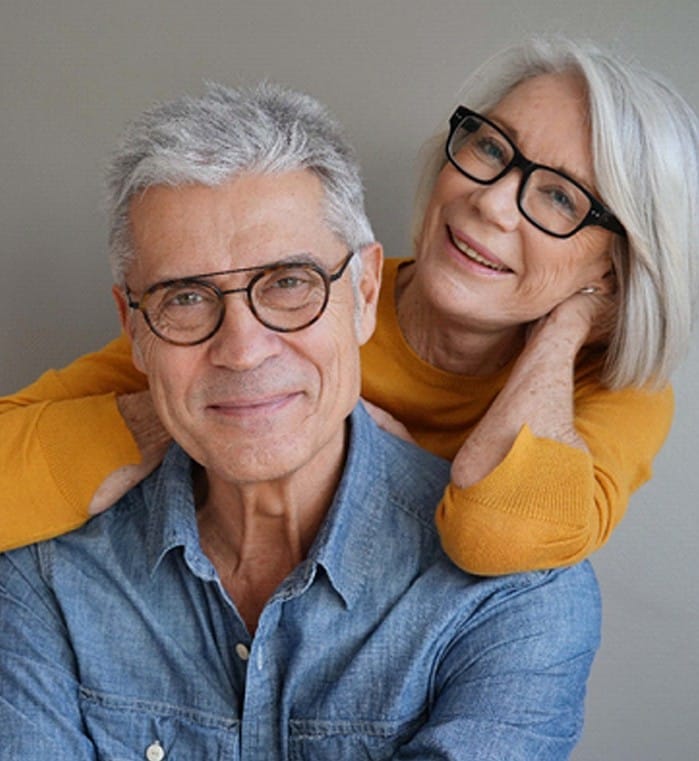 An older couple wearing glasses and smiling in preparation for their dental implants in Powdersville