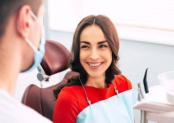 A young female smiling at her dentist as he explains the process for dental implant placement