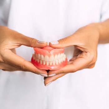 a person holding a brand new pair of dentures