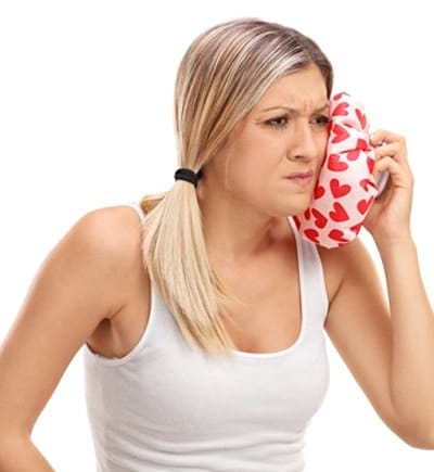 woman holding cold compress to her face