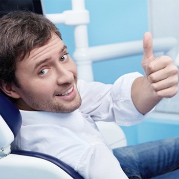 Male dental patient looking back and giving a thumbs up