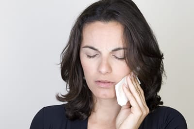 Woman with toothache holding cheek before tooth extraction