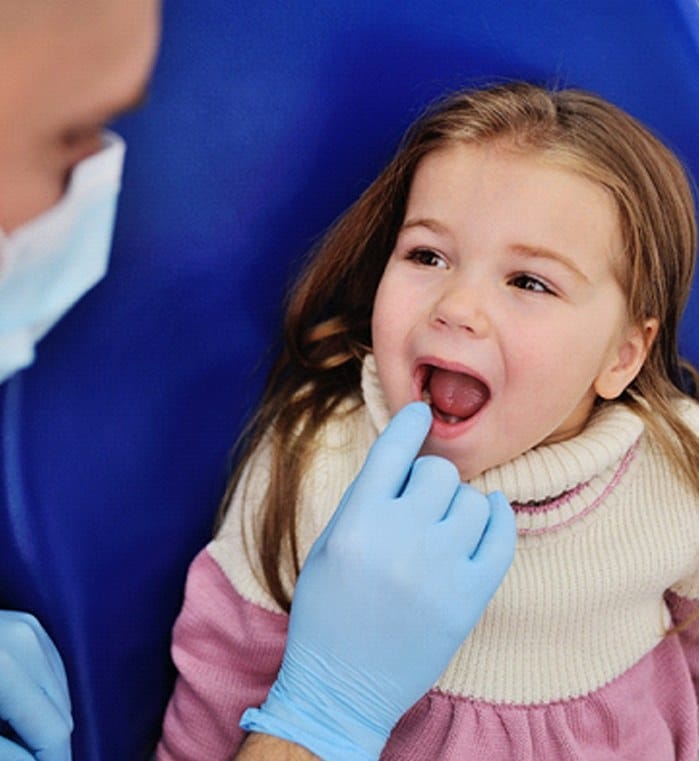 A dentist preparing to examine a little girl’s mouth during a regular appointment