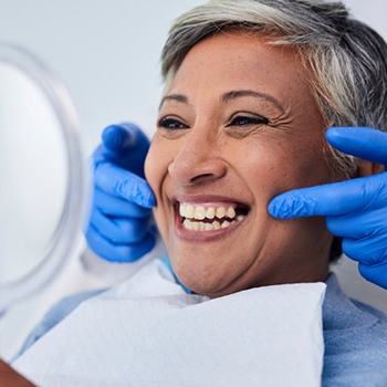 a patient checking her dental implants with a mirror