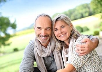 Middle-aged couple smiling together while sitting outside