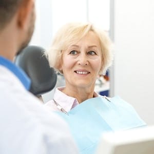 Older woman smiling while sitting in dental chair during appointment