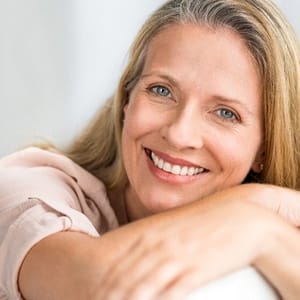 Woman with harms crossed around chair smiling while looking at camera