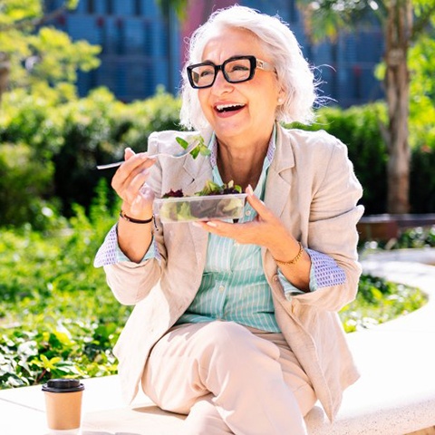 Lady smiles while eating salad
