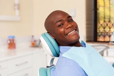 Smiling man in dental chair after receiving periodontal therapy