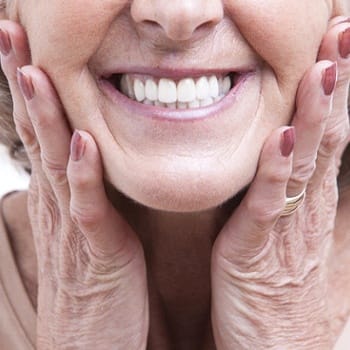 An up-close image of an older woman’s smile that has been restored with full dentures