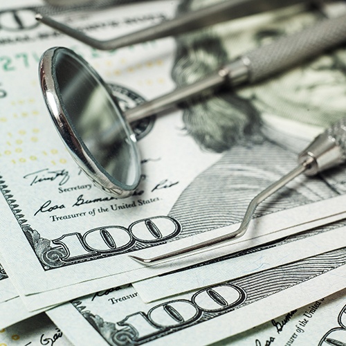 Dental tools lying on a stack of hundred-dollar bills