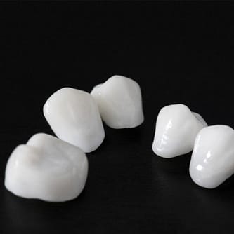 Several porcelain dental crowns arranged against dark background