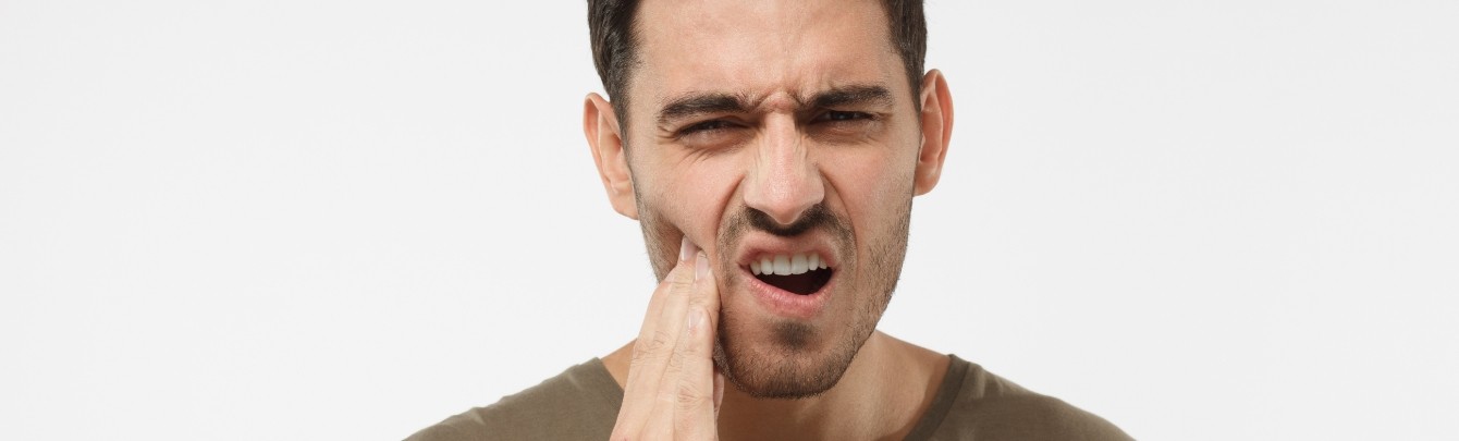 Woman in dental chair with her hand on her cheek before TMJ treatment