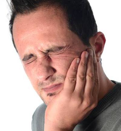 Man holding jaw in pain before TMJ treatment
