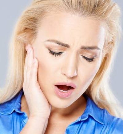 Woman holding cheek in pain in need of treatment for bruxism