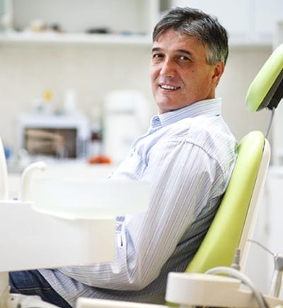 man in collared shirt smiling in dental chair