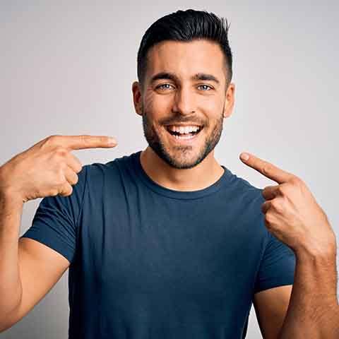 a patient smiling and pointing at their teeth