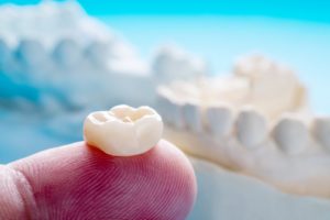 person holding a lost dental crown on their finger 