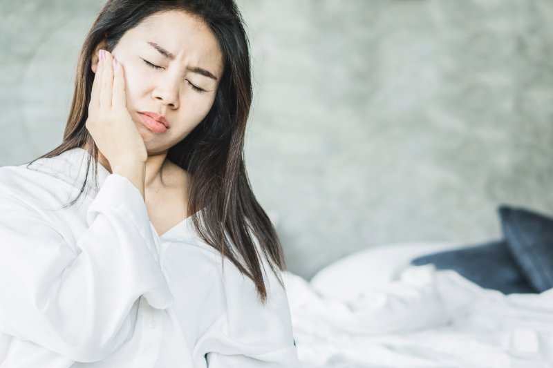 woman with facial swelling holding face