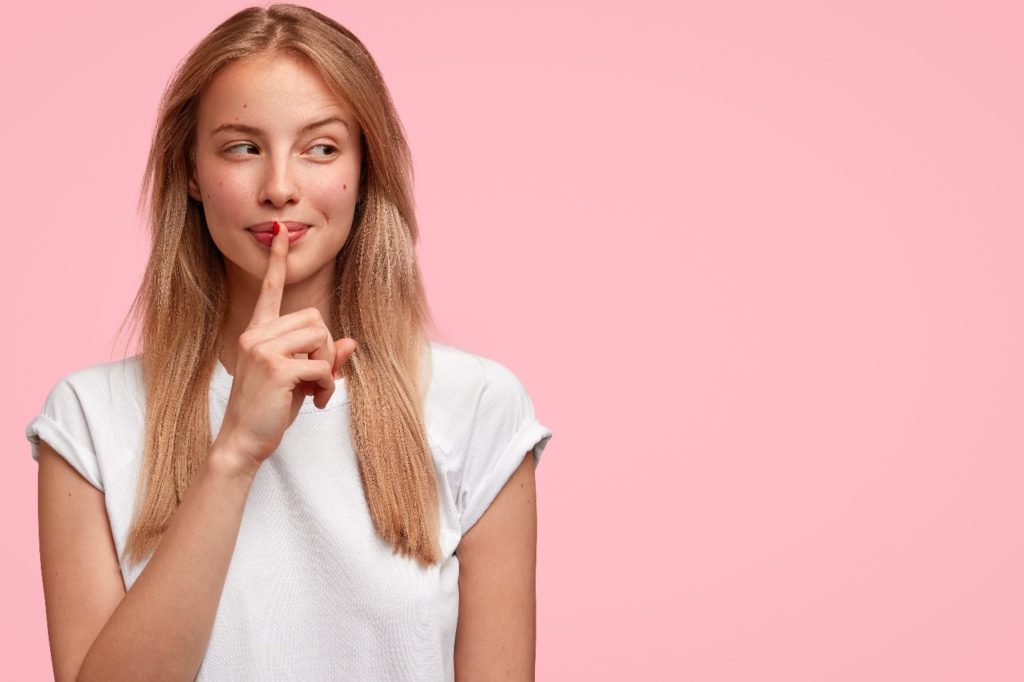 Woman in white shirt touching her finger to her lips