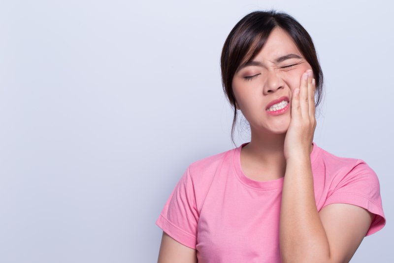 person with dental emergency holding cheek