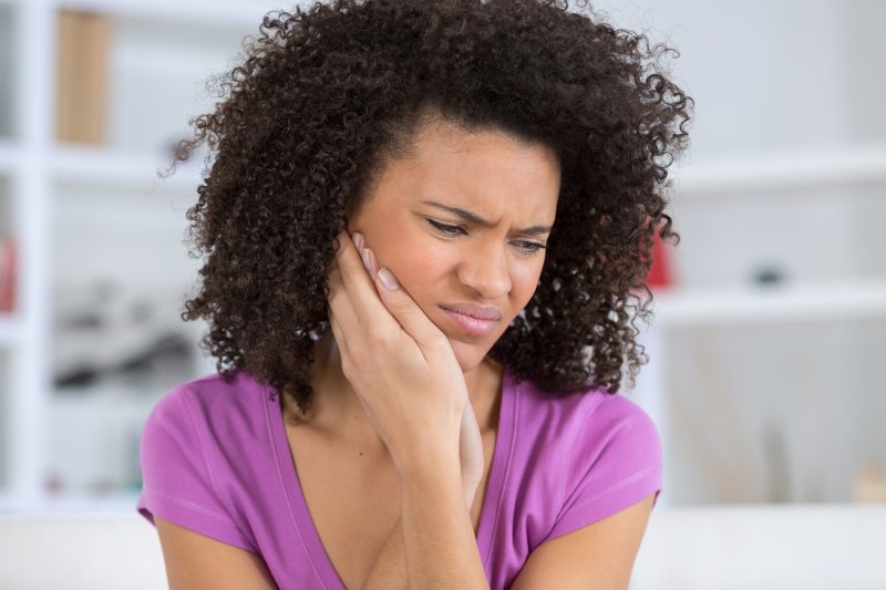 person with a dental emergency holding their cheek