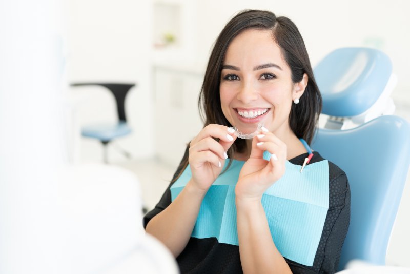 A woman holding clear aligners at a dental clinic