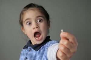 Girl holding lost tooth with surprised expression